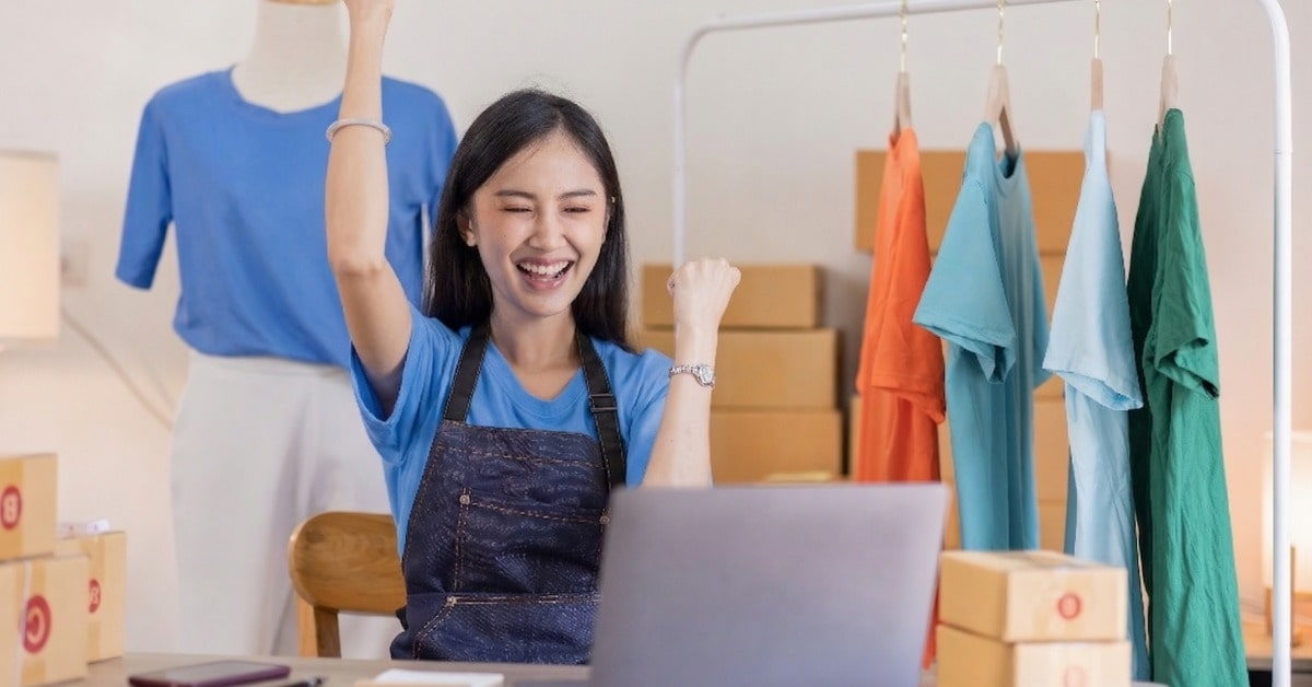 Empreendedora comemora em frente ao computador após criar loja virtual para iniciantes