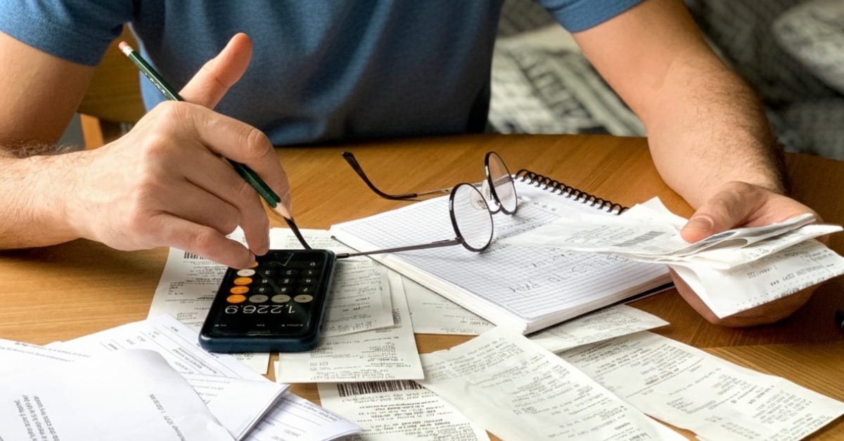 Homem em uma mesa com boletos e contas fazendo os cálculos de como parcelar mei atrasado